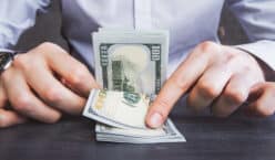 Businessman in shirt counting dollar banknotes on wooden table for free money and rewards