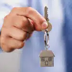 Holding out house keys on a house shaped keychain