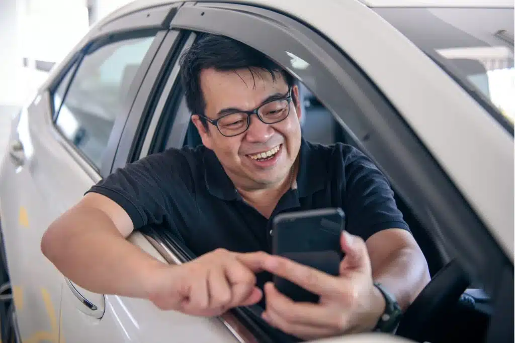 Uber Driver leaning out the car window using his phone