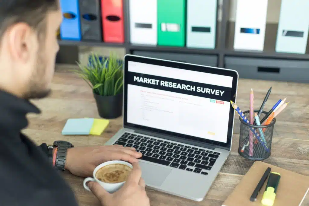 man filling out a market research survey on a laptop while drinking coffee